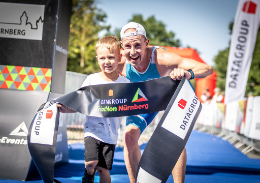 Sieger Kurzdistanz hält Banner mit Sohn